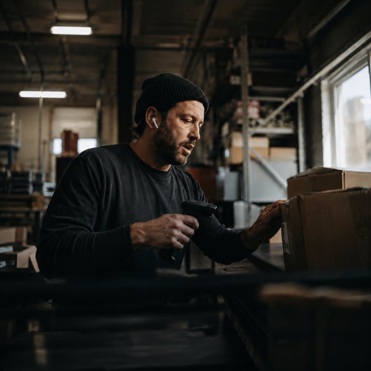 Warehouse worker scanning a box label, speaking his answer aloud with an earbud in